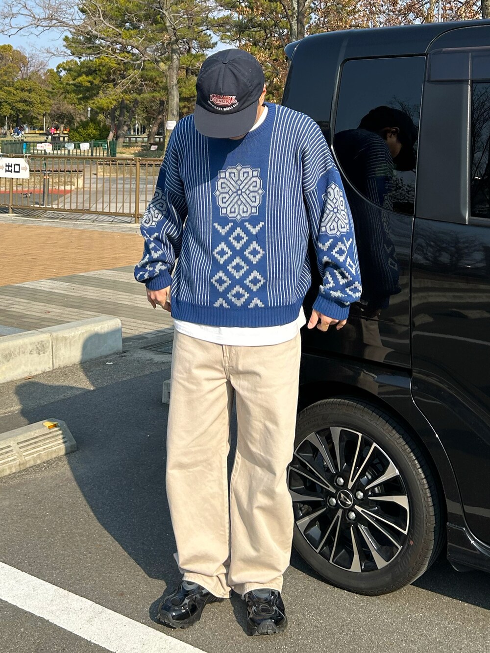 ブルー系のニット/セーター、ベージュ系のデニムパンツ、ブラック系のスニーカーを着用したメンズの冬コーディネートの2枚目の写真