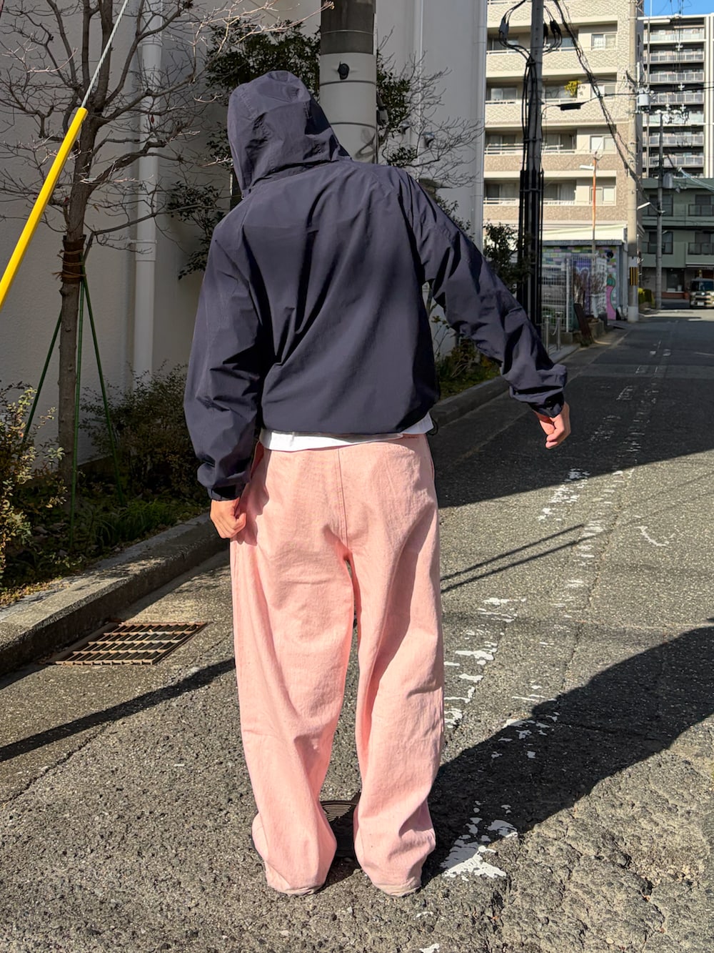 ピンク系のデニムパンツ、ブルー系のナイロンジャケット、ブラック系のスニーカーを着用したメンズの冬コーディネートの2枚目の写真