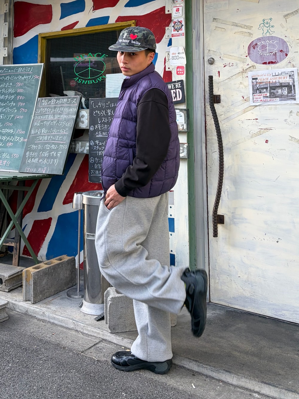 ブラック系のスウェット、パープル系のダウンベスト、グレー系のスウェットパンツを着用したメンズの冬コーディネートの2枚目の写真