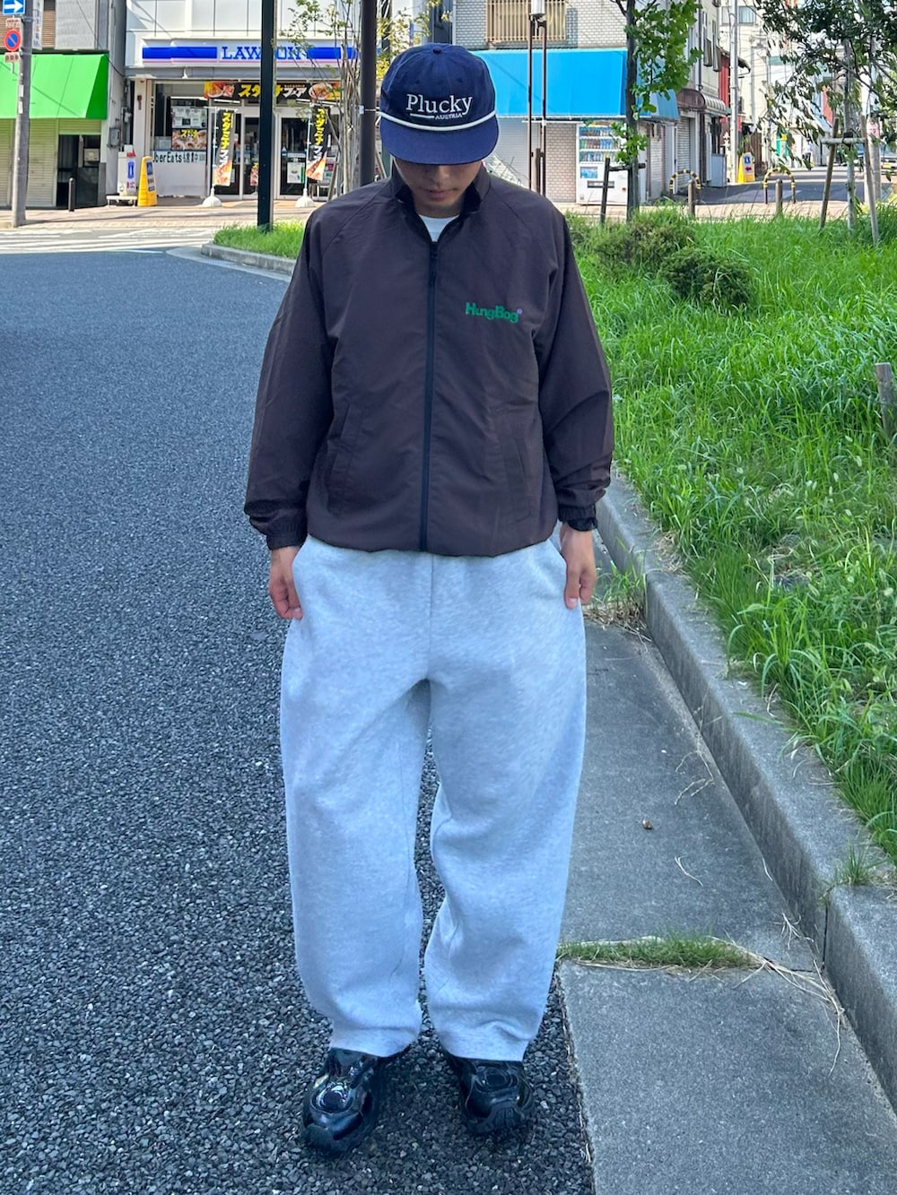 ブラウン系のナイロンジャケット、グレー系のスウェットパンツ、ブラック系のスニーカーを着用したメンズの秋コーディネートの2枚目の写真