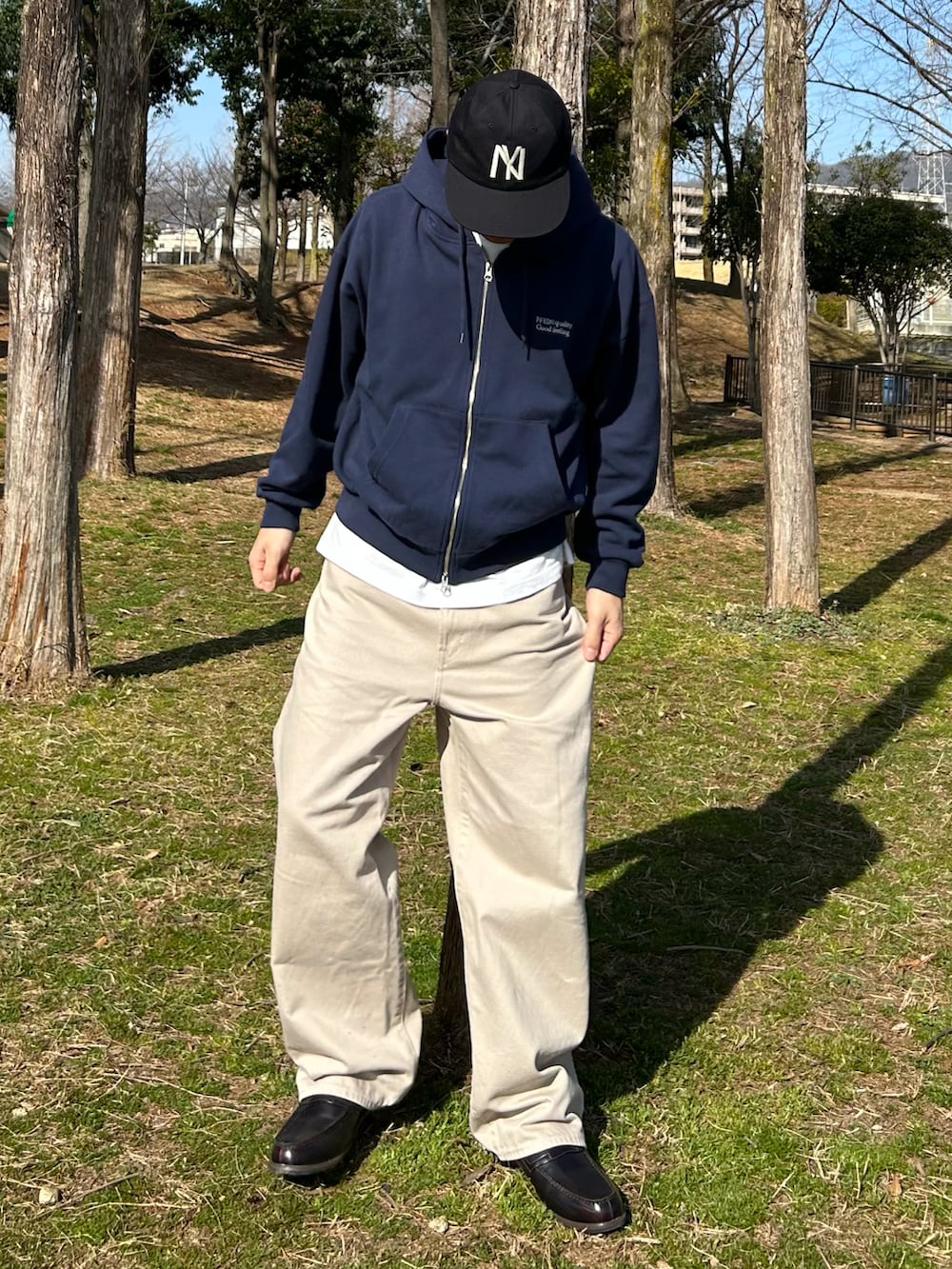 ブルー系のパーカー、ベージュ系のデニムパンツ、ブラウン系のローファーを着用したメンズの春コーディネートの2枚目の写真