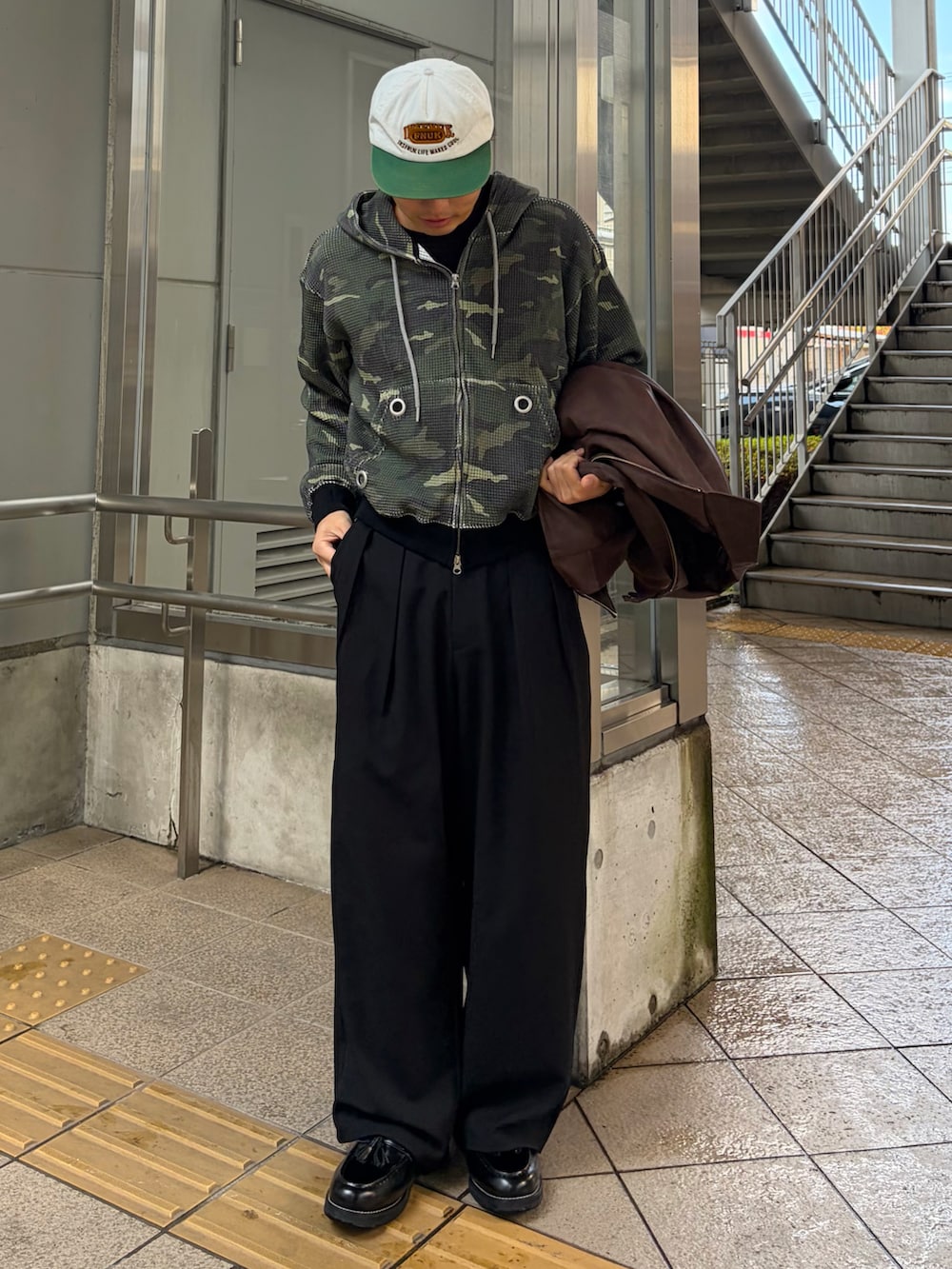 ブラック系のローファー、グリーン系のパーカー、ブラック系のスラックスを着用したメンズの冬コーディネートの2枚目の写真