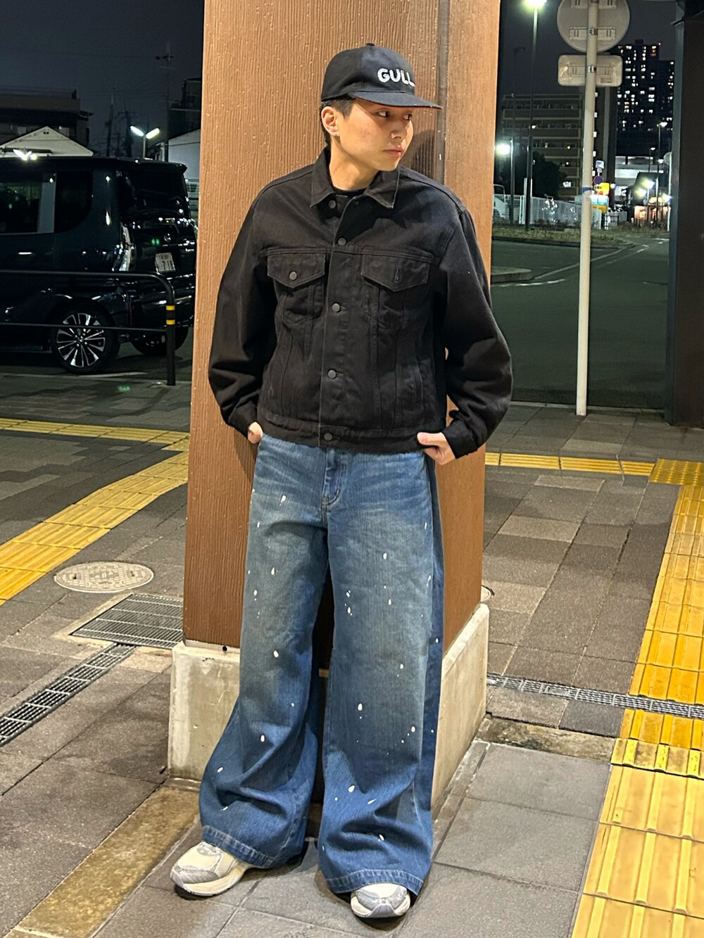 ブラック系のデニムジャケット、ブルー系のデニムパンツ、シルバー系のスニーカーを着用したメンズの春コーディネートの2枚目の写真