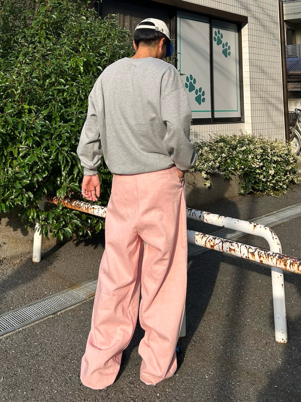 ピンク系のデニムパンツ、グレー系のスウェット、ブラック系のスニーカーを着用したメンズの秋コーディネートの2枚目の写真