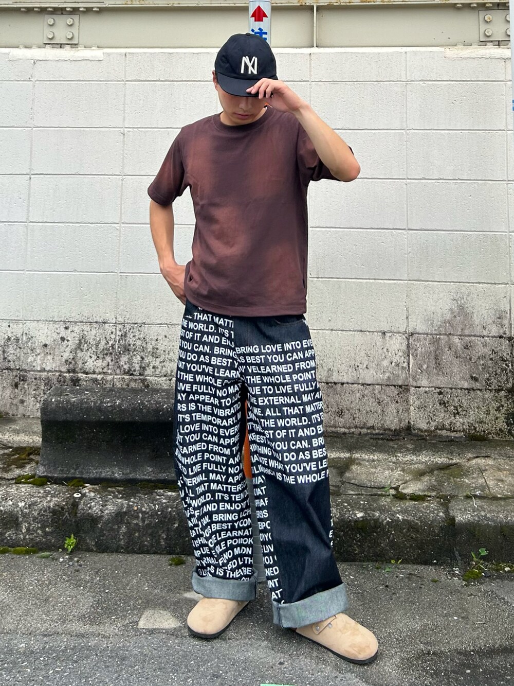 ブルー系のデニムパンツ、ベージュ系のサンダル、ブラウン系のTシャツ/カットソーを着用したメンズの夏コーディネートの2枚目の写真