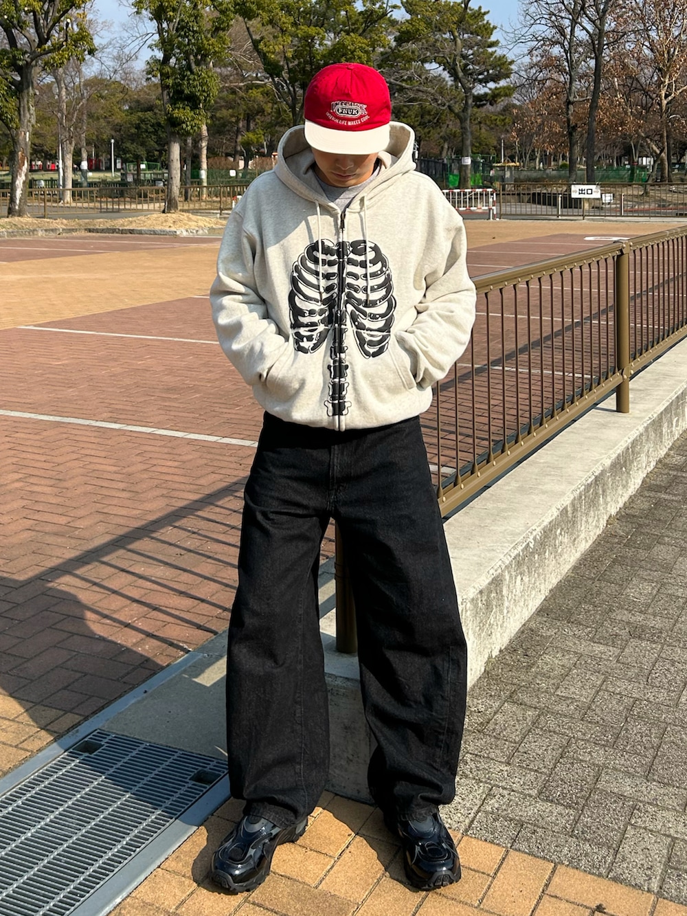 グレー系のパーカー、ブラック系のデニムパンツ、ブラック系のスニーカーを着用したメンズの冬コーディネートの2枚目の写真