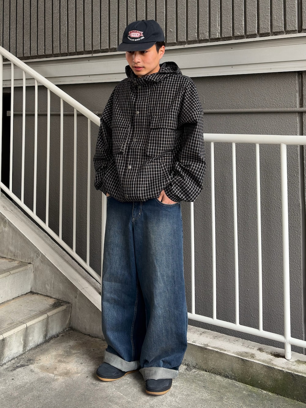 ブルー系のデニムパンツ、ブラック系のパーカー、ブラック系のスニーカーを着用したメンズの春コーディネートの2枚目の写真