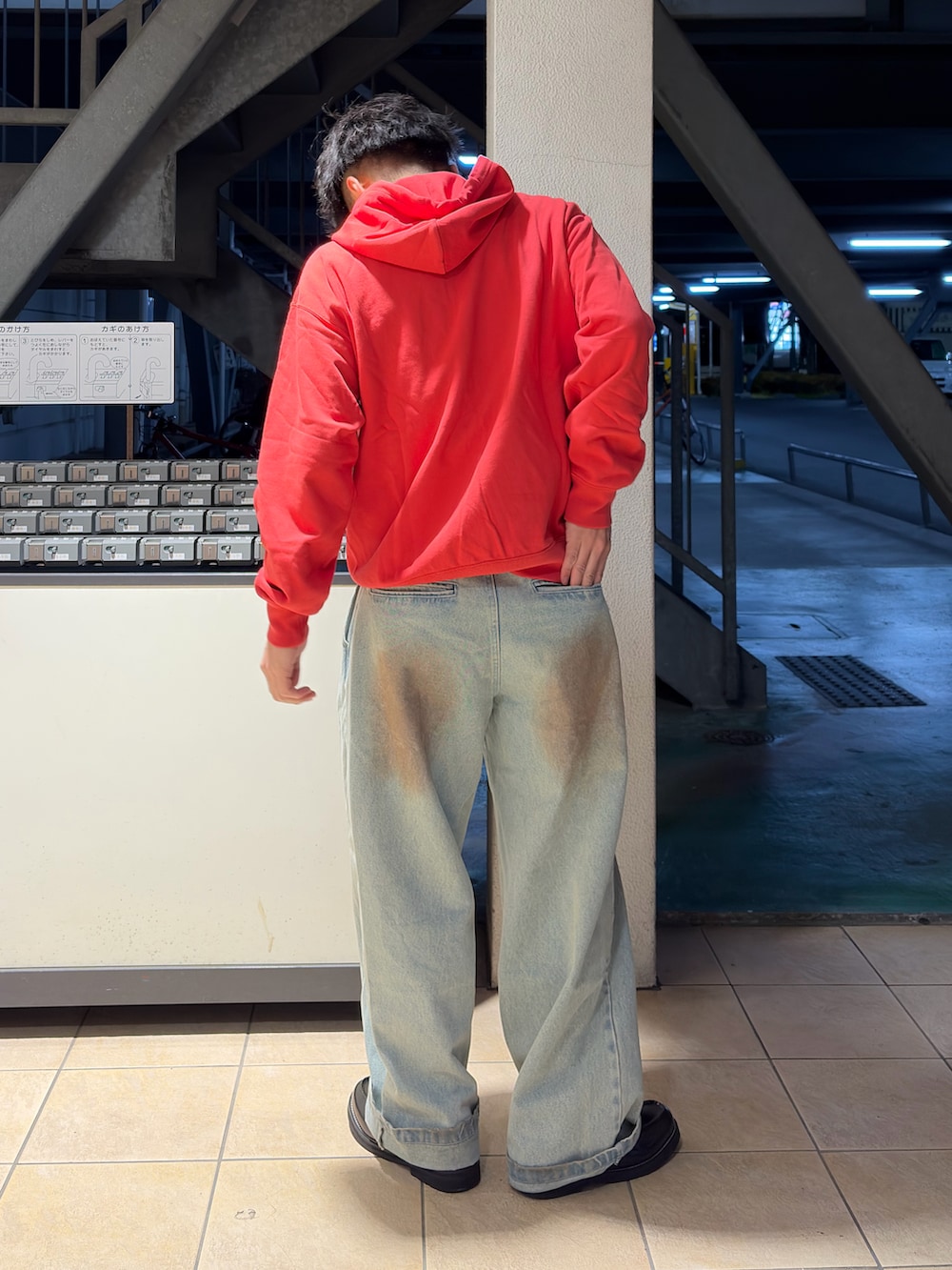 ブルー系のデニムパンツ、ブラック系のローファー、レッド系のパーカーを着用したメンズの春コーディネートの2枚目の写真