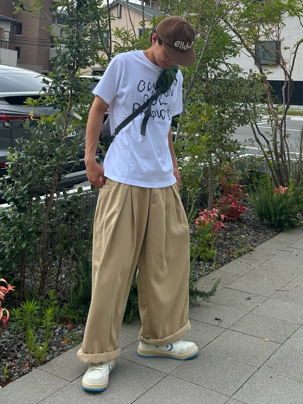 ホワイト系のスニーカー、ホワイト系のTシャツ/カットソー、ベージュ系のスラックスを着用したメンズの夏コーディネートの2枚目の写真