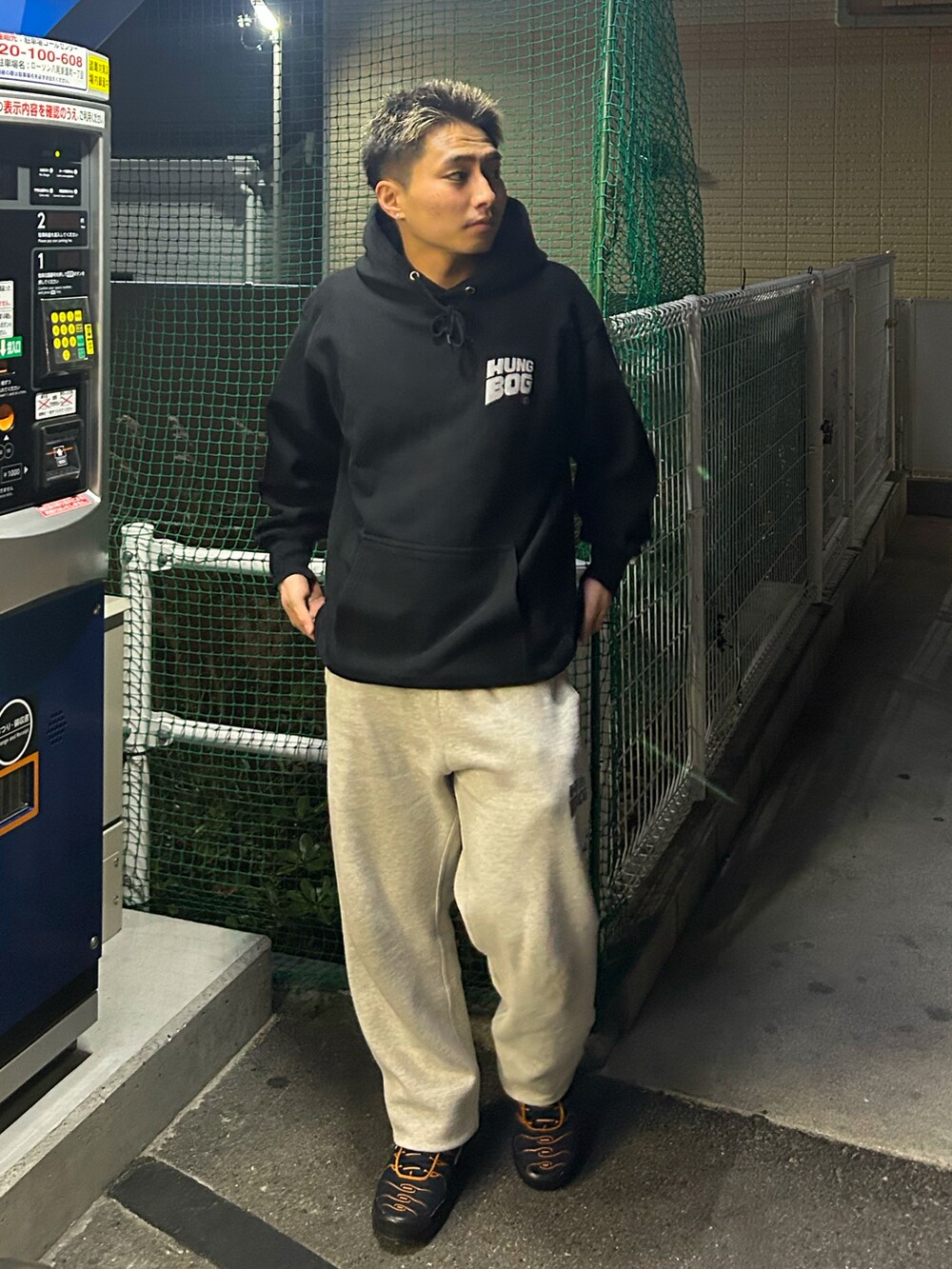 グレー系のスウェットパンツ、ブラック系のスニーカー、ブラック系のパーカーを着用したメンズの冬コーディネートの2枚目の写真