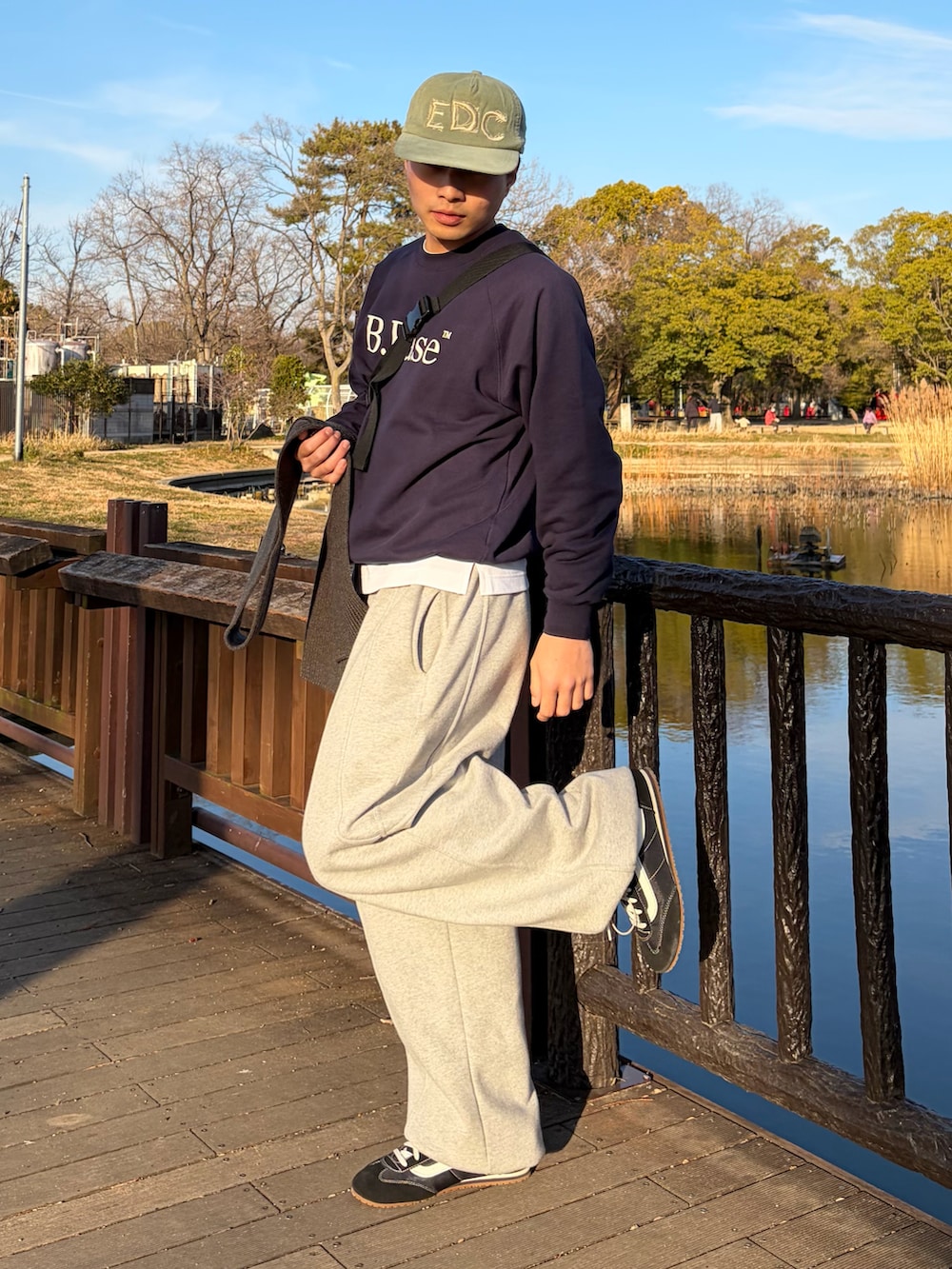 ブルー系のスウェット、グレー系のスウェットパンツ、ブラック系のスニーカーを着用したメンズの春コーディネートの2枚目の写真