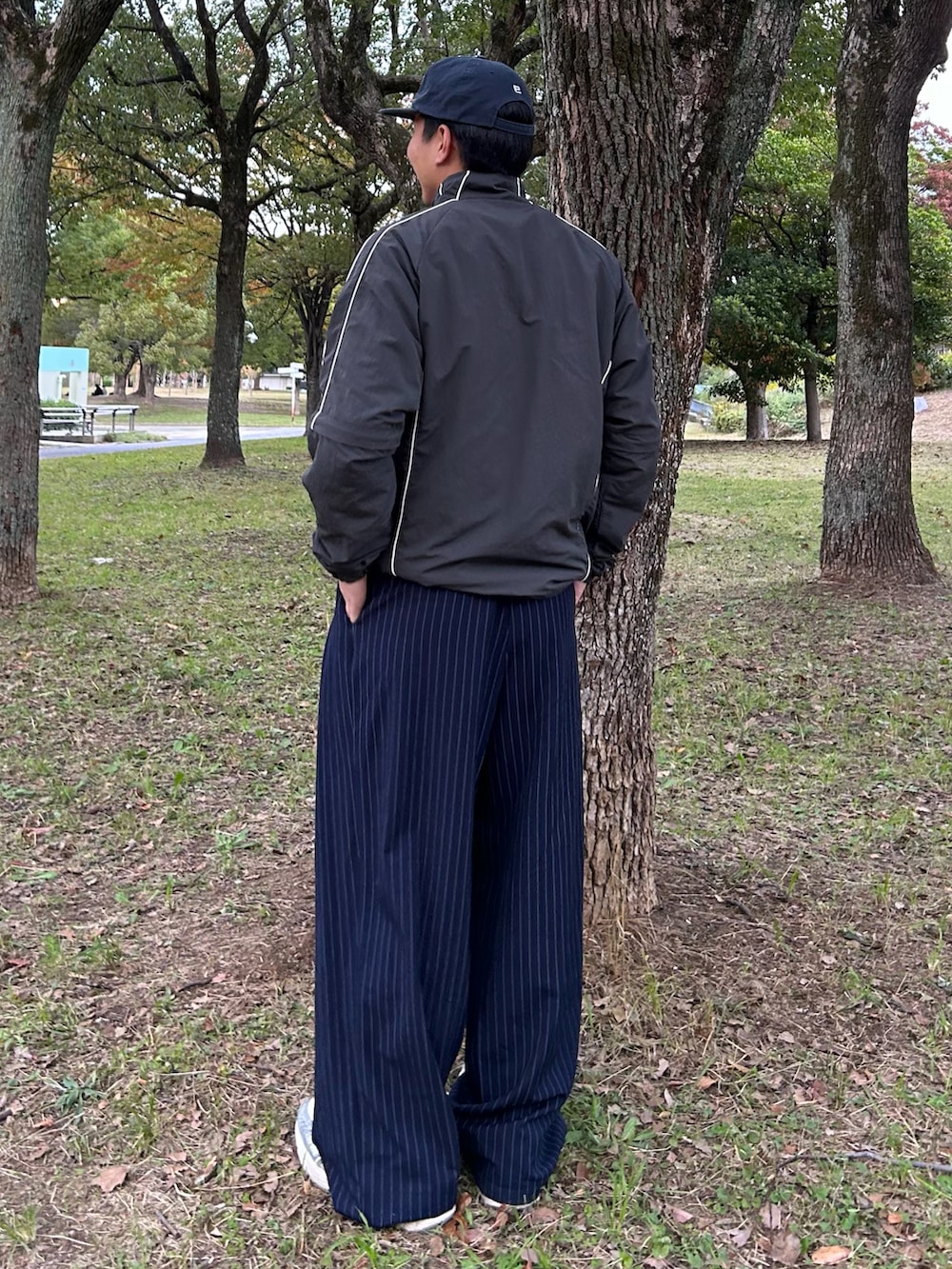 グレー系のナイロンジャケット、ブルー系のスラックス、シルバー系のスニーカーを着用したメンズの冬コーディネートの2枚目の写真