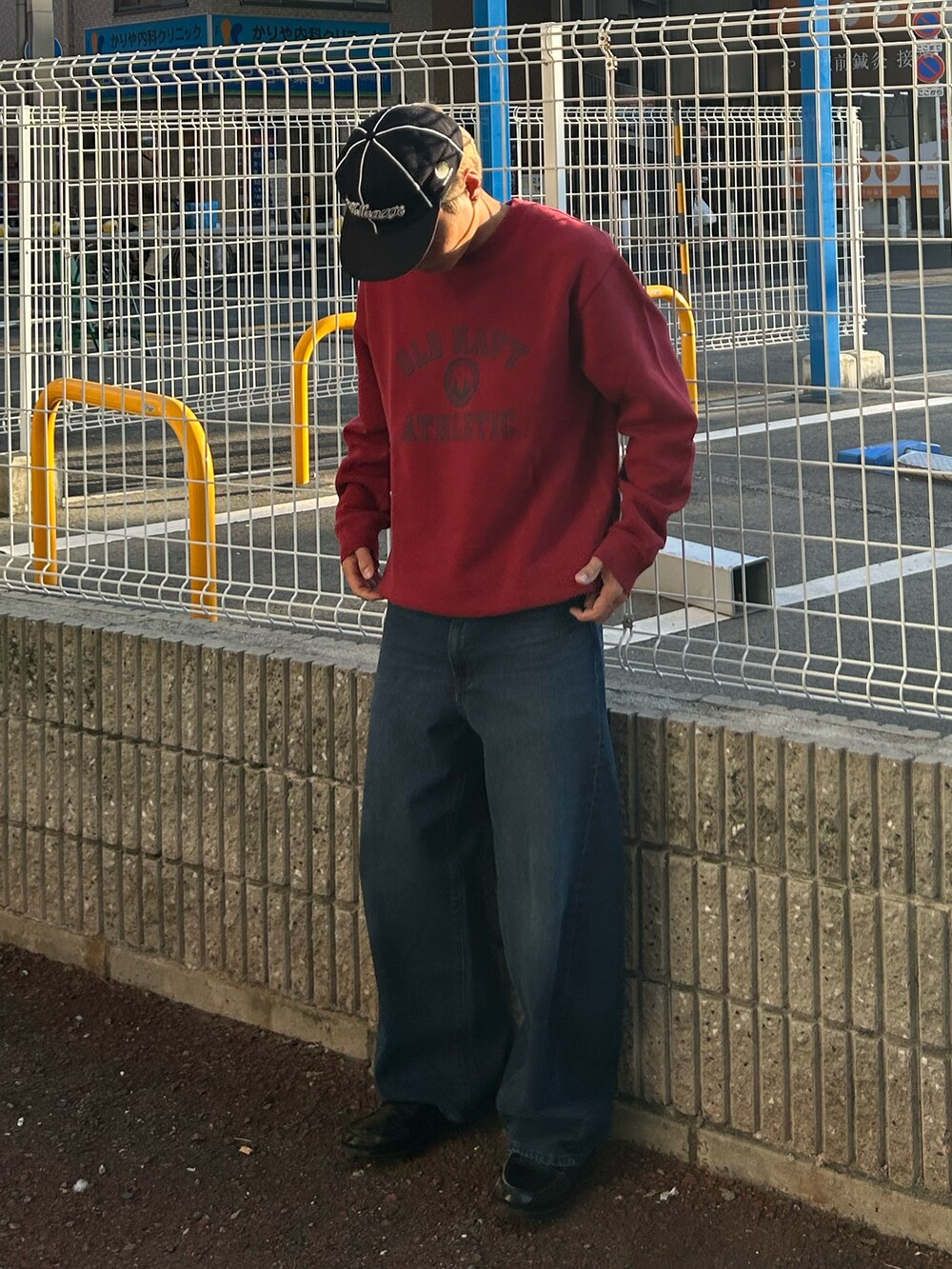 レッド系のスウェット、ブルー系のデニムパンツ、ブラック系のローファーを着用したメンズの秋コーディネートの2枚目の写真