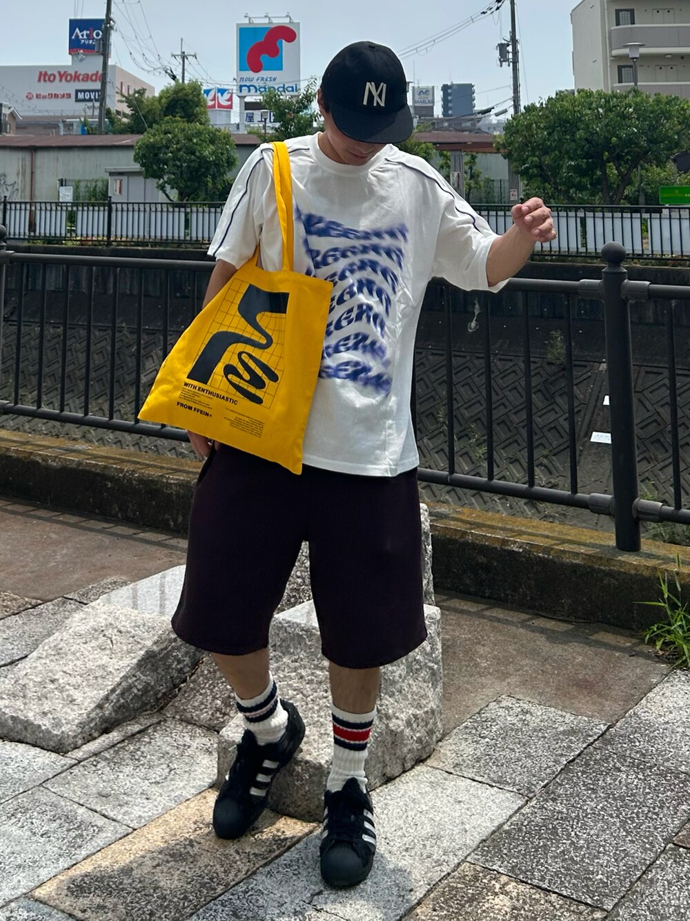 ホワイト系のTシャツ/カットソー、ブラウン系のスウェットパンツ、イエロー系のトートバッグを着用したメンズの夏コーディネートの2枚目の写真