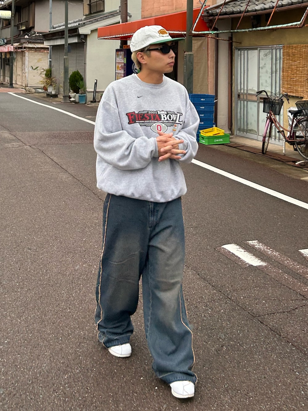 グレー系のスウェット、ブルー系のデニムパンツ、ホワイト系のスニーカーを着用したメンズの秋コーディネートの2枚目の写真