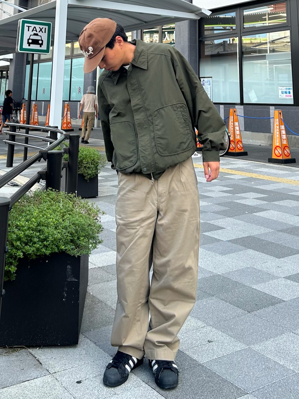 グリーン系のテーラードジャケット、ベージュ系のデニムパンツ、ブラック系のスニーカーを着用したメンズの秋コーディネートの2枚目の写真