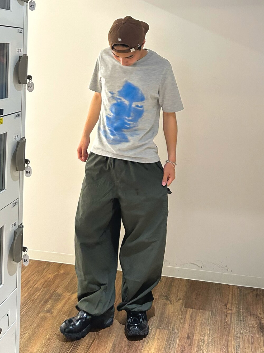 グリーン系のカーゴパンツ、グレー系のTシャツ/カットソー、ブラック系のスニーカーを着用したメンズの夏コーディネートの3枚目の写真