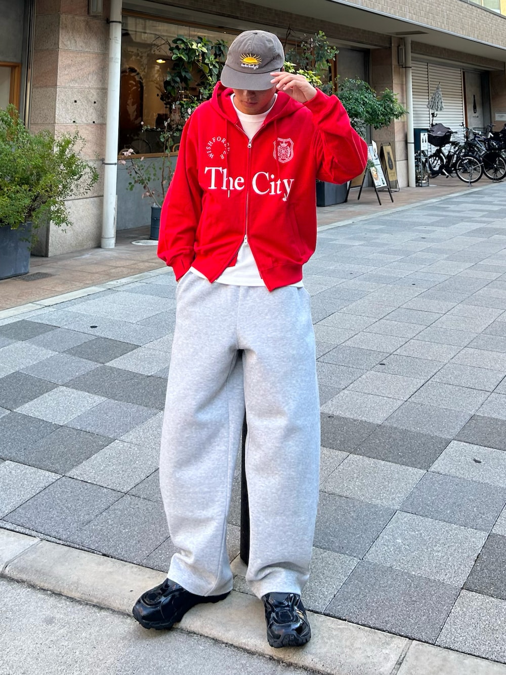 レッド系のパーカー、グレー系のスウェットパンツ、ブラック系のスニーカーを着用したメンズの秋コーディネートの2枚目の写真