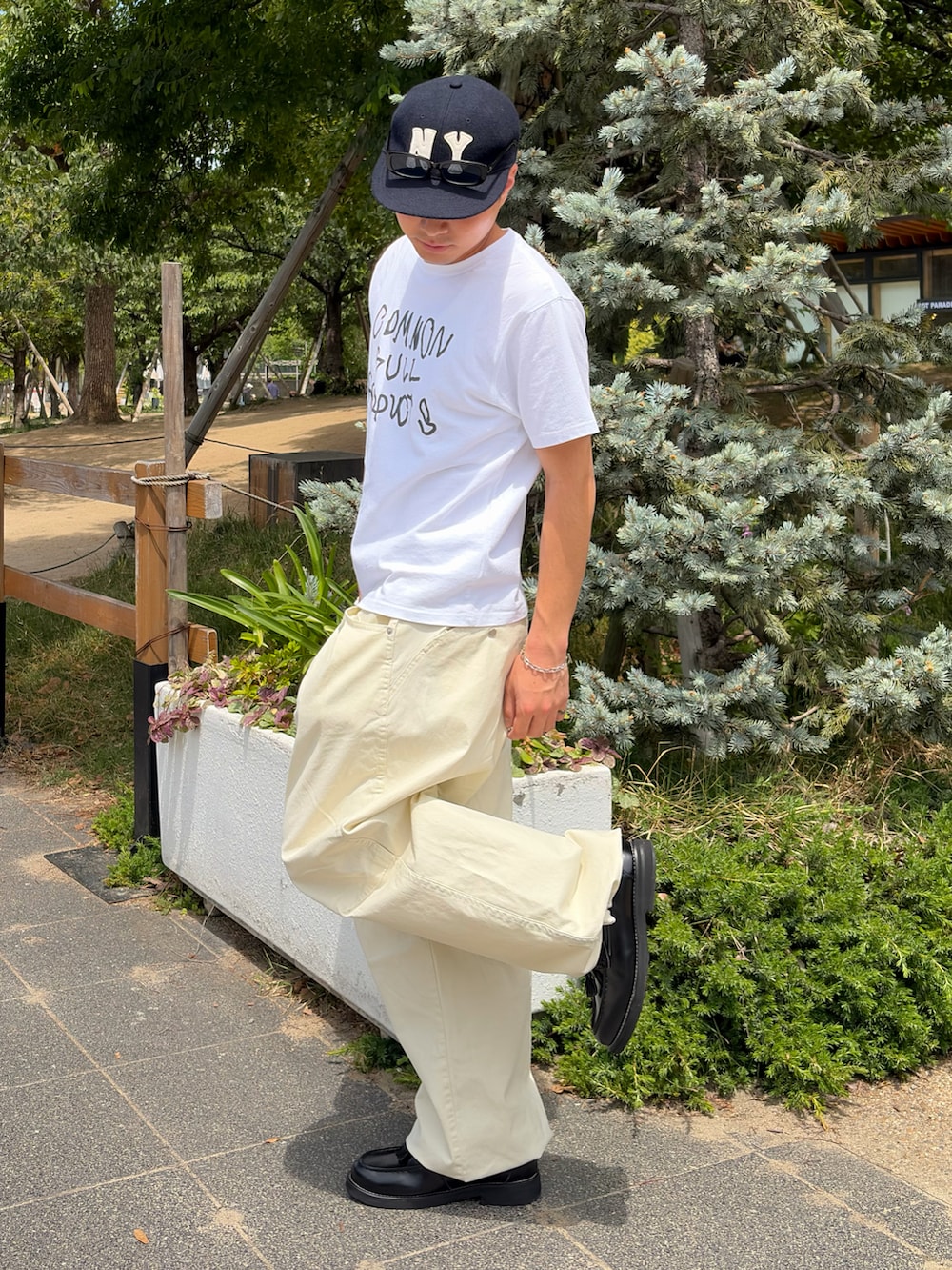 ホワイト系のTシャツ/カットソー、ホワイト系のスラックス、ブラック系のローファーを着用したメンズの夏コーディネートの2枚目の写真