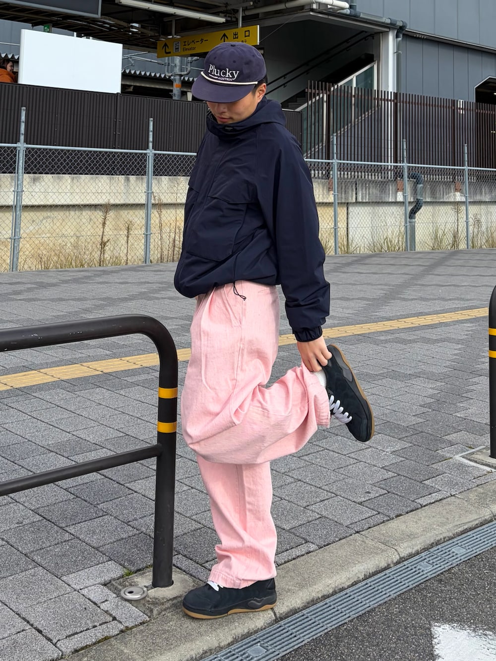 ピンク系のデニムパンツ、ブルー系のナイロンジャケット、ブラック系のスニーカーを着用したメンズの冬コーディネートの2枚目の写真