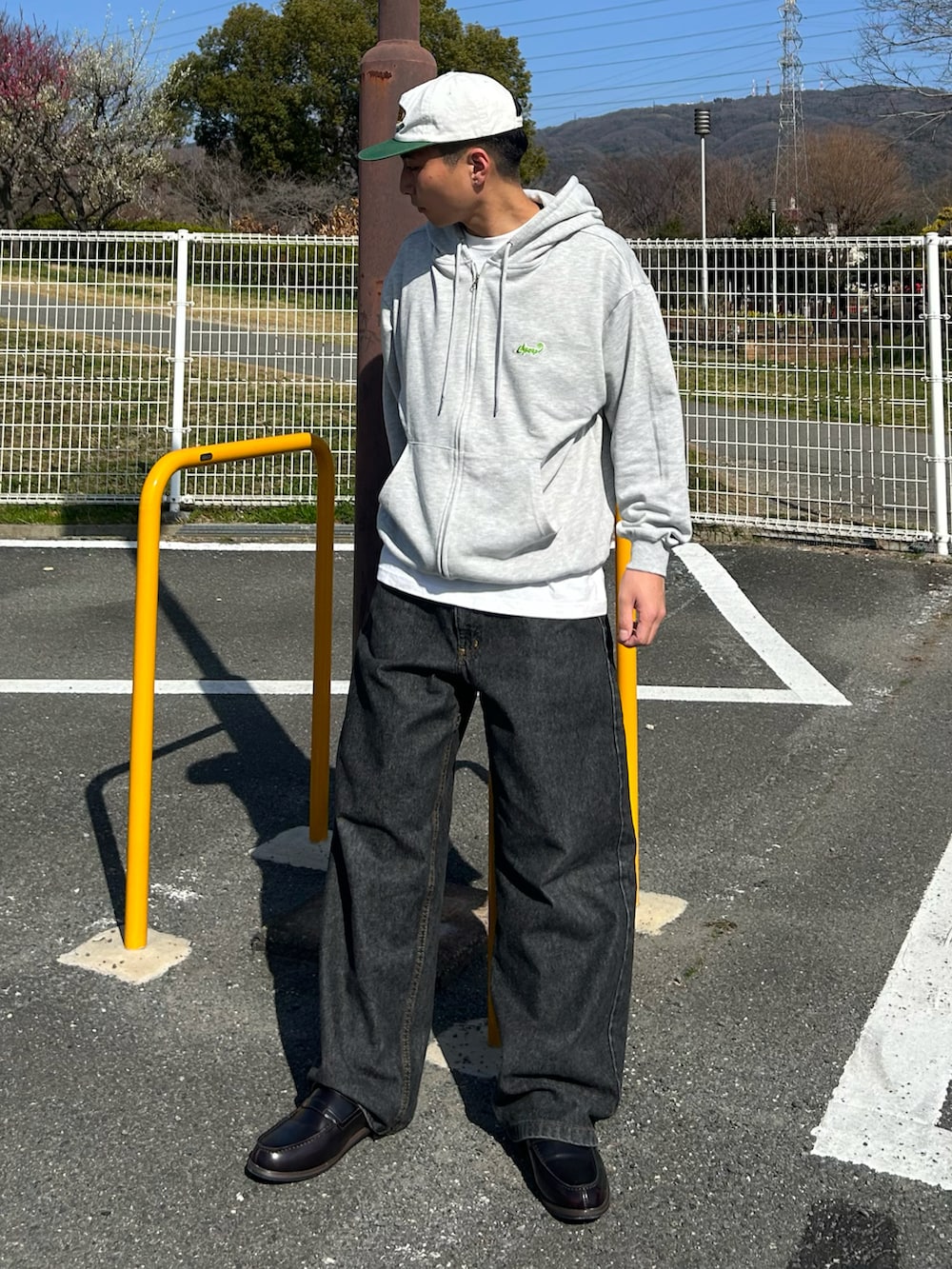 グレー系のパーカー、ブラック系のデニムパンツ、ブラウン系のローファーを着用したメンズの春コーディネートの2枚目の写真