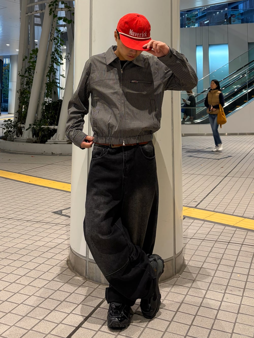 グレー系のブルゾン、ブラック系のデニムパンツ、ブラック系のスニーカーを着用したメンズの冬コーディネートの2枚目の写真