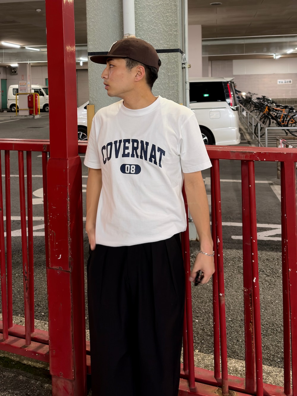 ホワイト系のTシャツ/カットソー、ブラック系のスラックス、ブラウン系のキャップを着用したメンズの春コーディネートの2枚目の写真