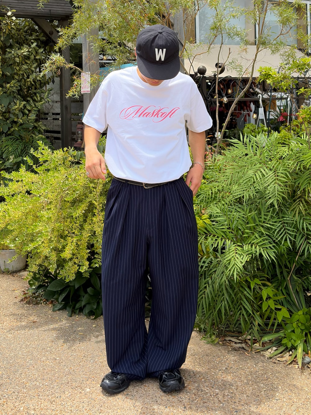 ホワイト系のTシャツ/カットソー、ブルー系のスラックス、ブラック系のスニーカーを着用したメンズの夏コーディネートの2枚目の写真