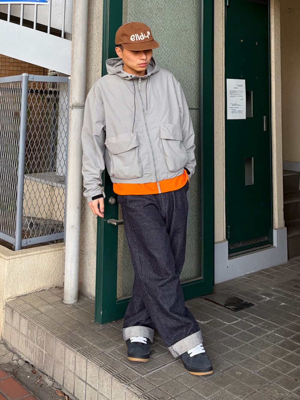 オレンジ系のTシャツ/カットソー、ブルー系のデニムパンツ、グレー系のジャケット/アウターを着用したメンズの冬コーディネートの2枚目の写真