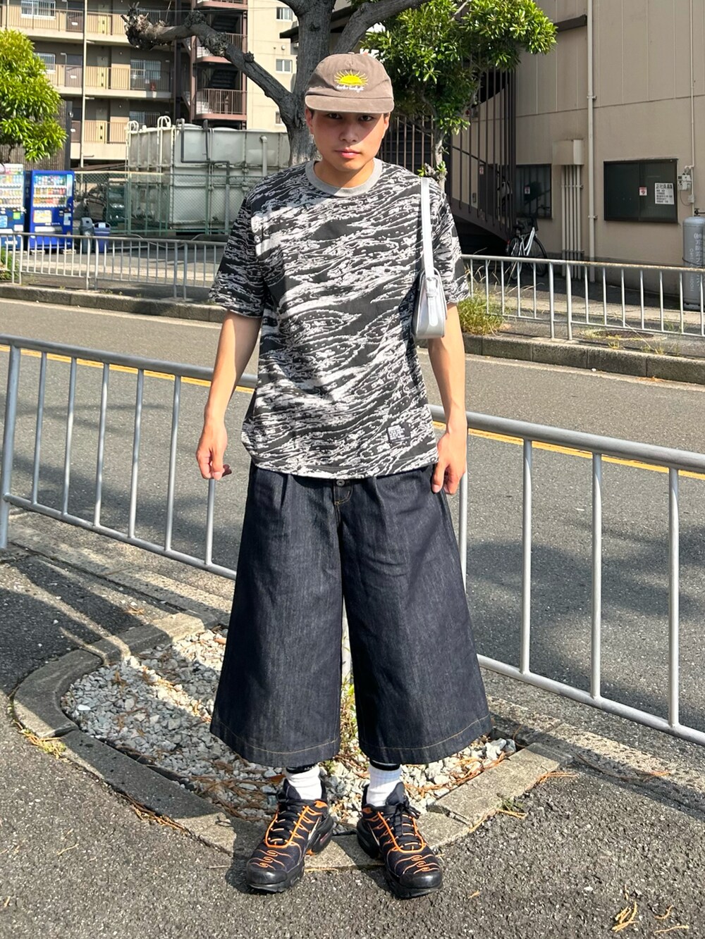 グレー系のTシャツ/カットソー、ブルー系のデニムパンツ、ブラック系のスニーカーを着用したメンズの夏コーディネートの2枚目の写真