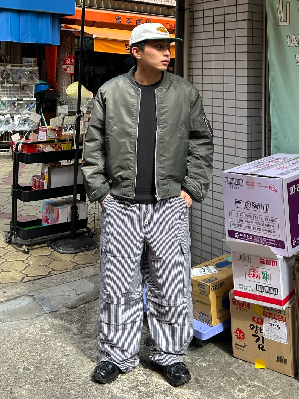 グリーン系のMA-1、ブラック系のカーゴパンツ、ブラック系のスニーカーを着用したメンズの冬コーディネートの2枚目の写真