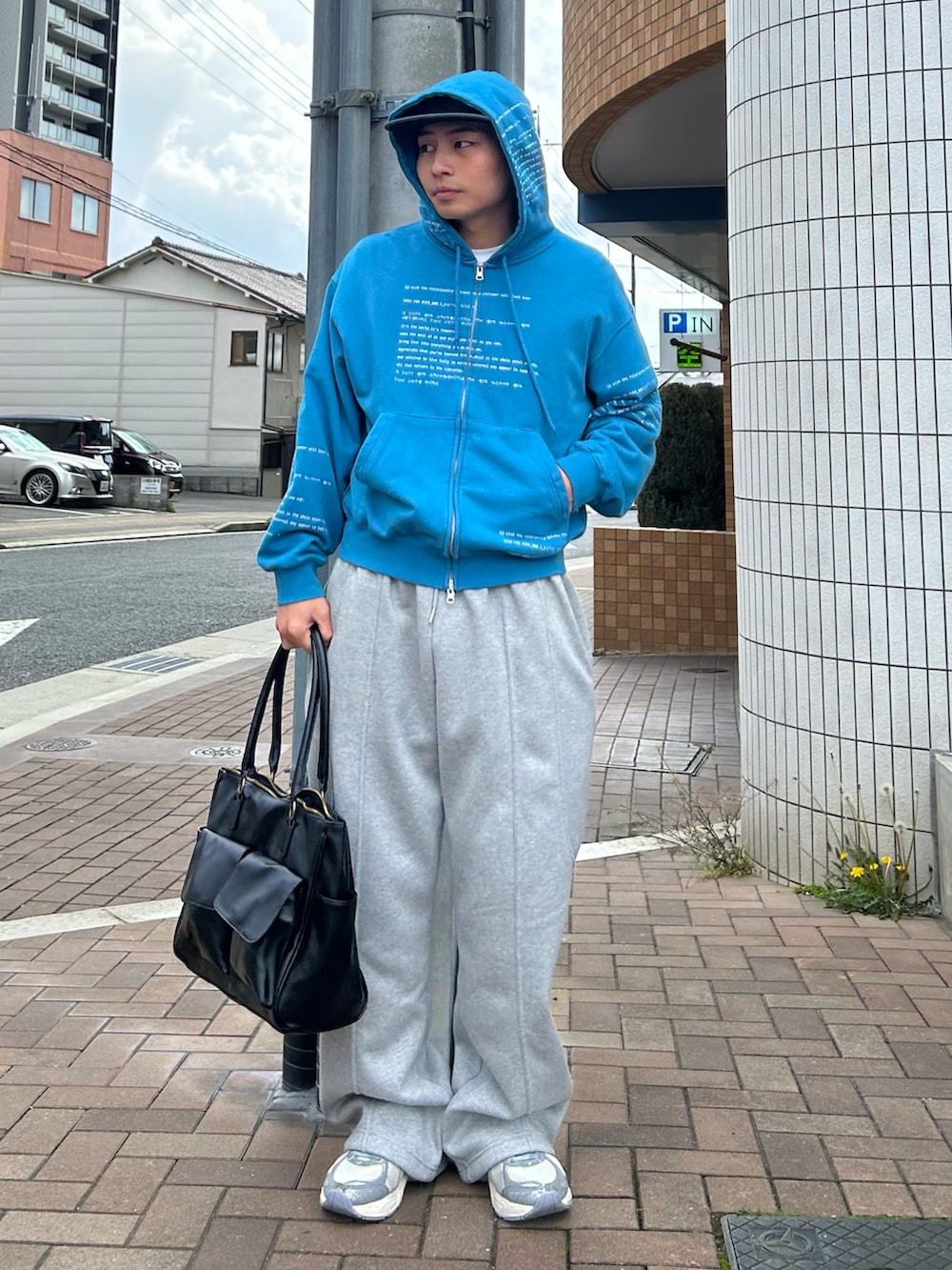 ブルー系のパーカー、ブラック系のボストンバッグ、グレー系のスウェットパンツを着用したメンズの春コーディネートの2枚目の写真