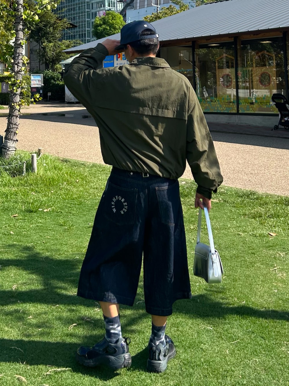 ブルー系のデニムパンツ、グリーン系のテーラードジャケット、シルバー系のショルダーバッグを着用したメンズの秋コーディネートの2枚目の写真