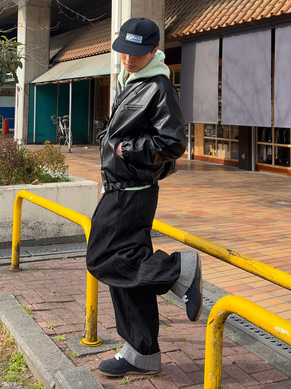 ブラック系のブルゾン、グリーン系のパーカー、ブラック系のデニムパンツを着用したメンズの春コーディネートの2枚目の写真