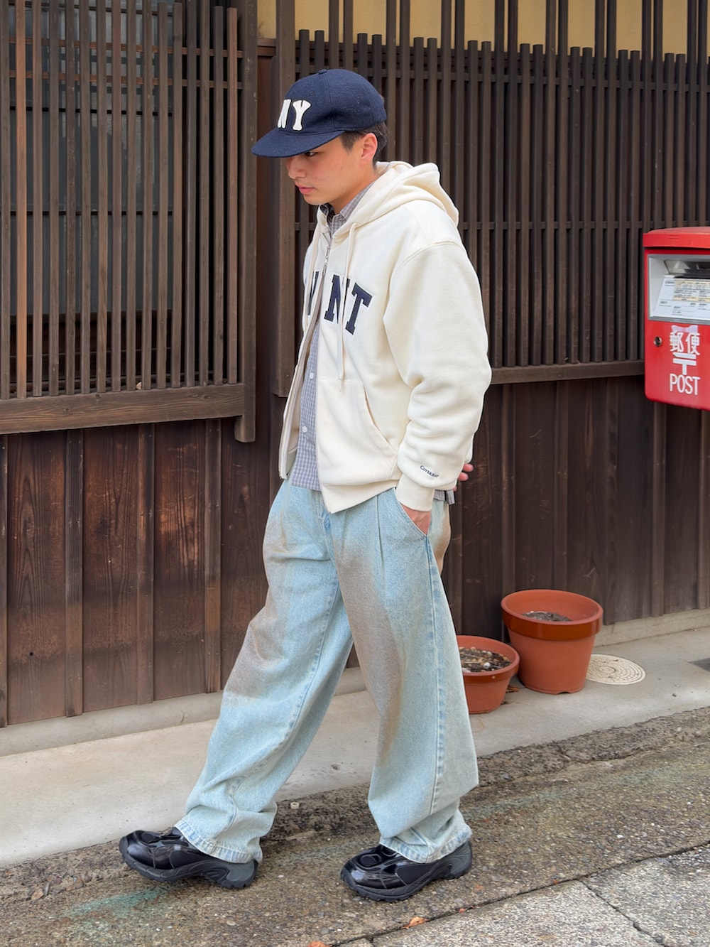 ブルー系のデニムパンツ、ホワイト系のパーカー、ブラック系のスニーカーを着用したメンズの春コーディネートの3枚目の写真