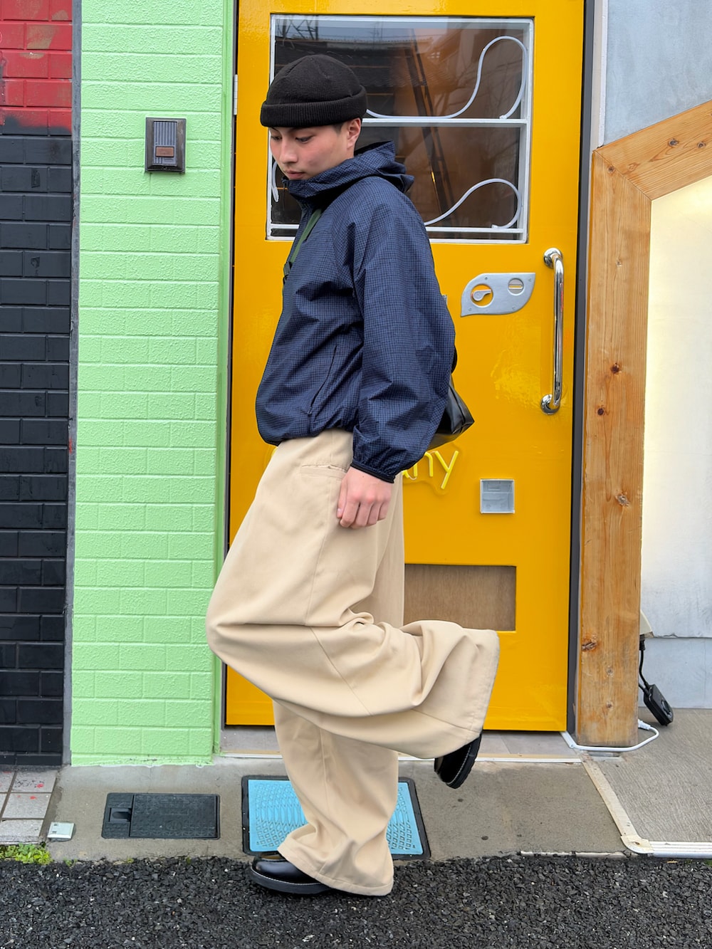 ベージュ系のスラックス、その他のメッセンジャーバッグ、ブラック系のローファーを着用したメンズの春コーディネートの2枚目の写真