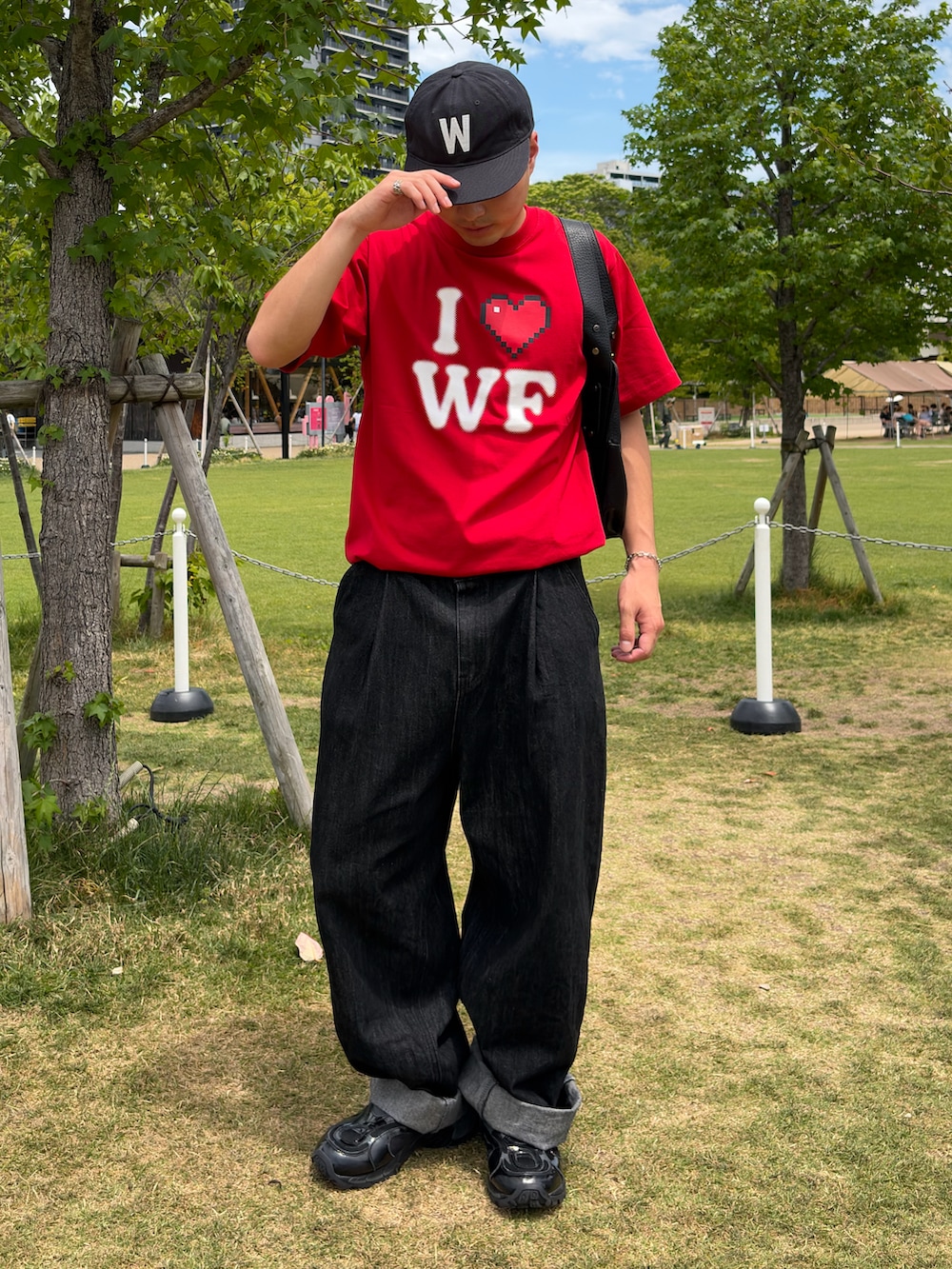 レッド系のTシャツ/カットソー、ブラック系のデニムパンツ、ブラック系のスニーカーを着用したメンズの夏コーディネートの2枚目の写真