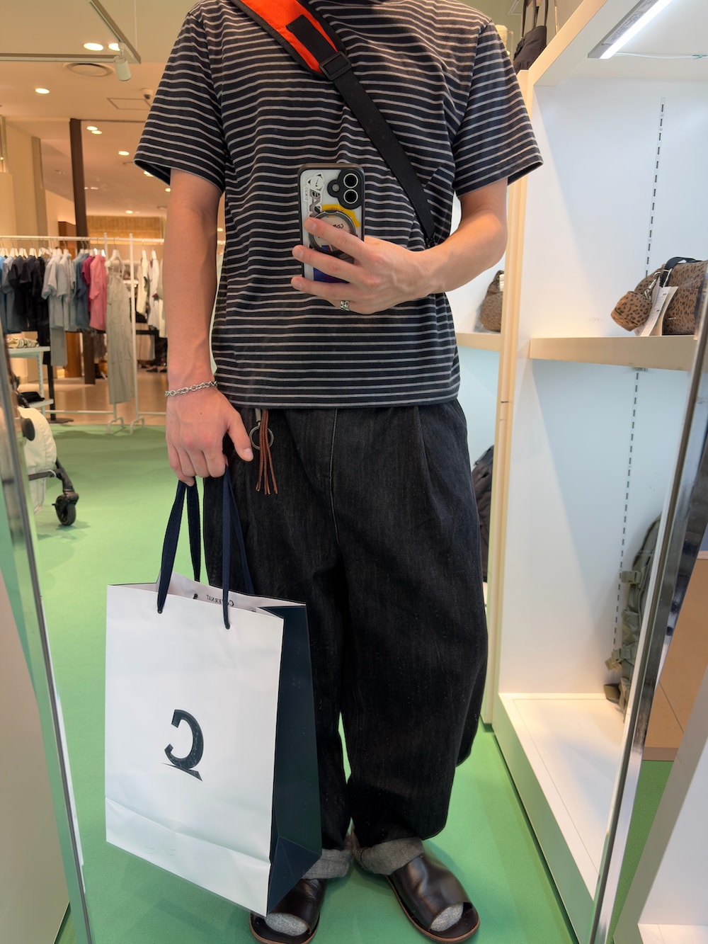 ブラック系のTシャツ/カットソー、ブラック系のデニムパンツ、オレンジ系のショルダーバッグを着用したメンズの秋コーディネートの2枚目の写真