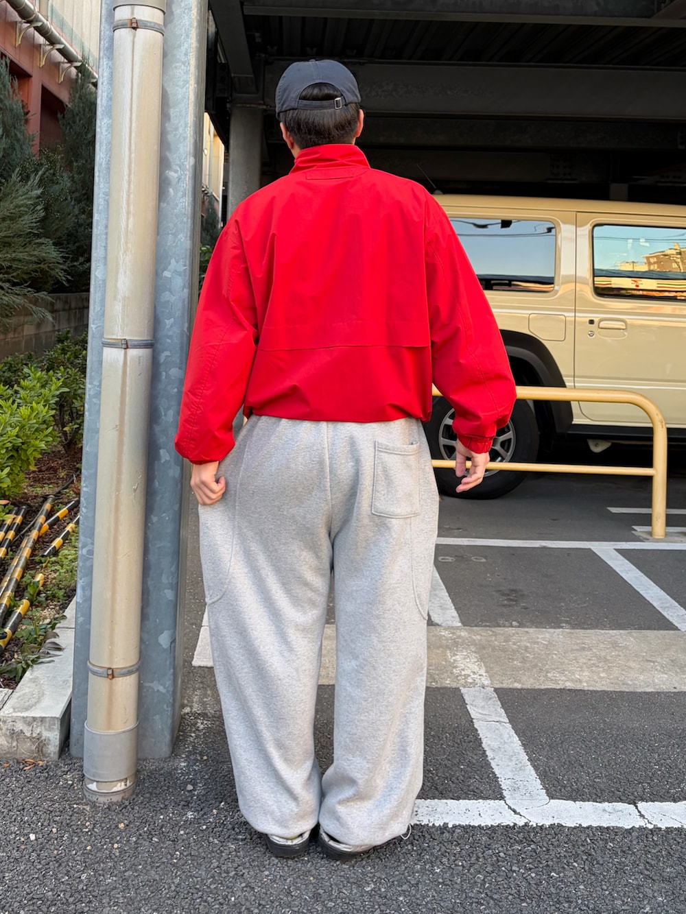 シルバー系のサンダル、レッド系のナイロンジャケット、グレー系のスウェットパンツを着用したメンズの冬コーディネートの2枚目の写真