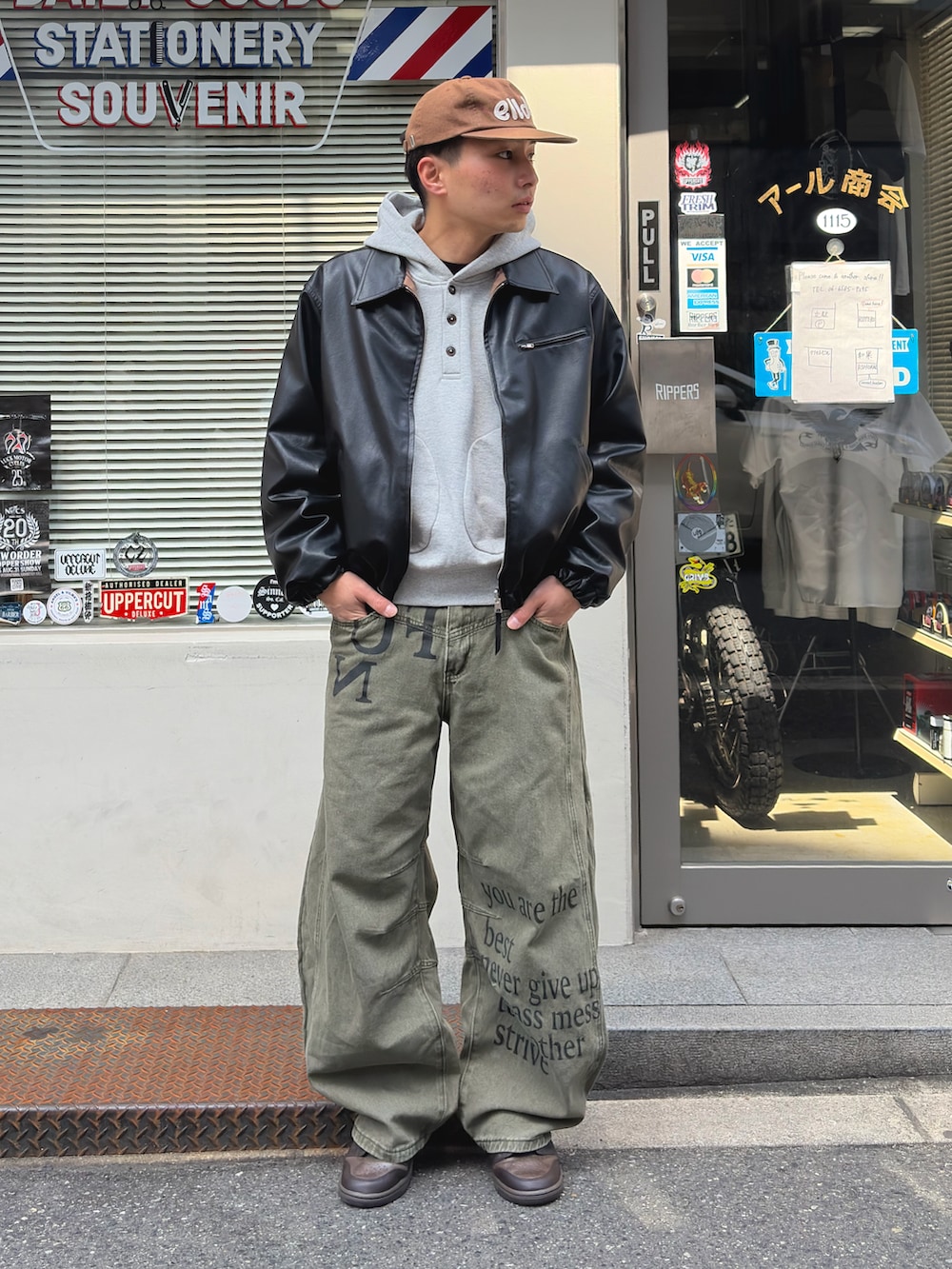 グレー系のパーカー、ブラック系のブルゾン、ブラウン系のスニーカーを着用したメンズの春コーディネートの2枚目の写真
