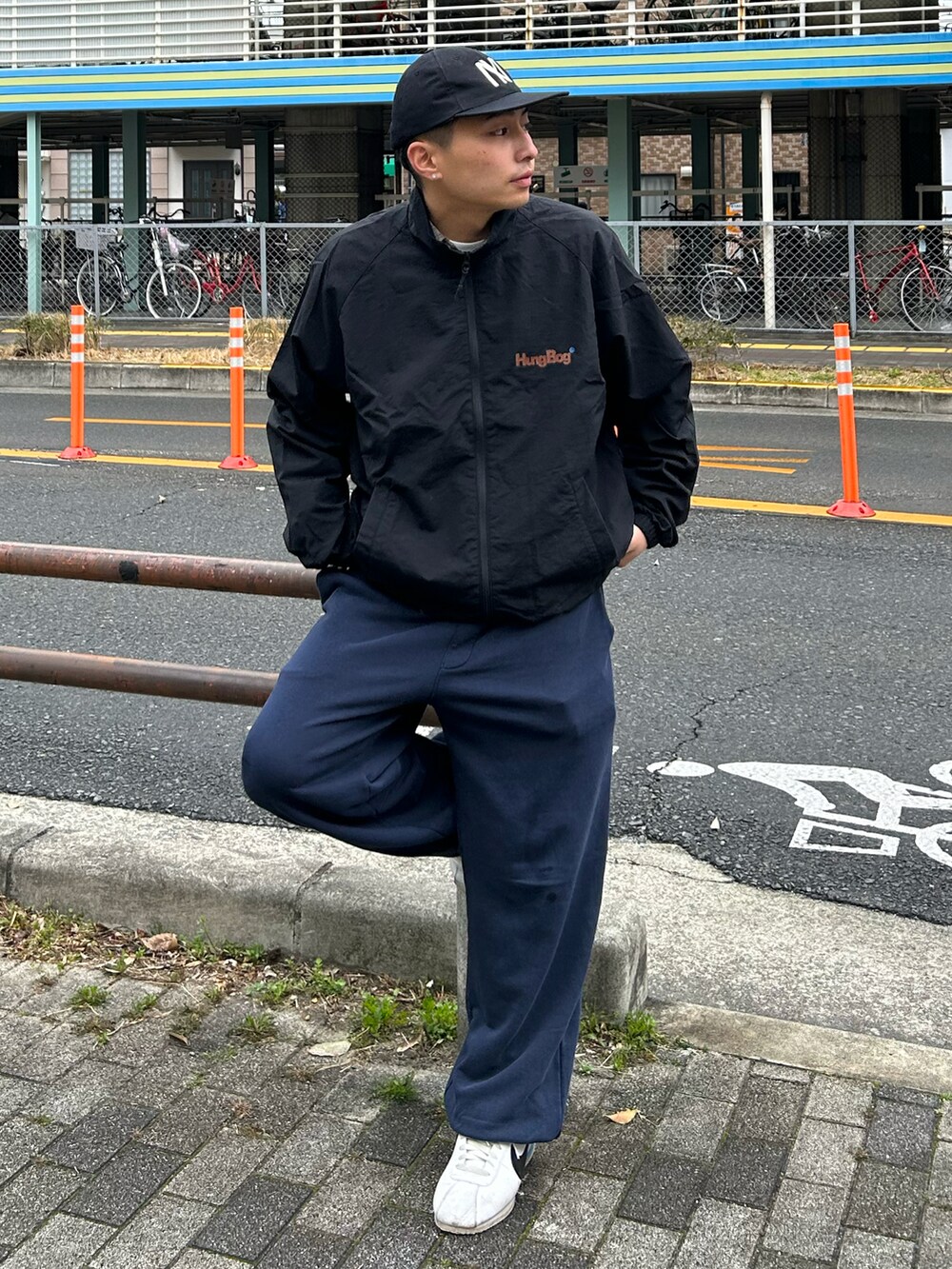 ブラック系のナイロンジャケット、ブルー系のスウェットパンツ、ホワイト系のスニーカーを着用したメンズの春コーディネートの2枚目の写真