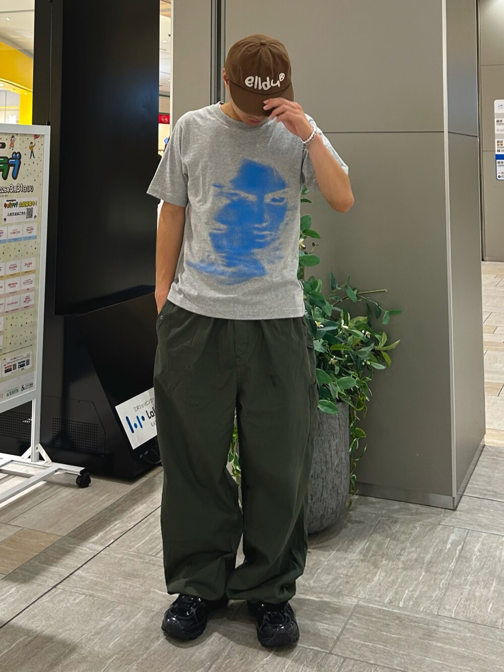グリーン系のカーゴパンツ、グレー系のTシャツ/カットソー、ブラック系のスニーカーを着用したメンズの夏コーディネートの2枚目の写真