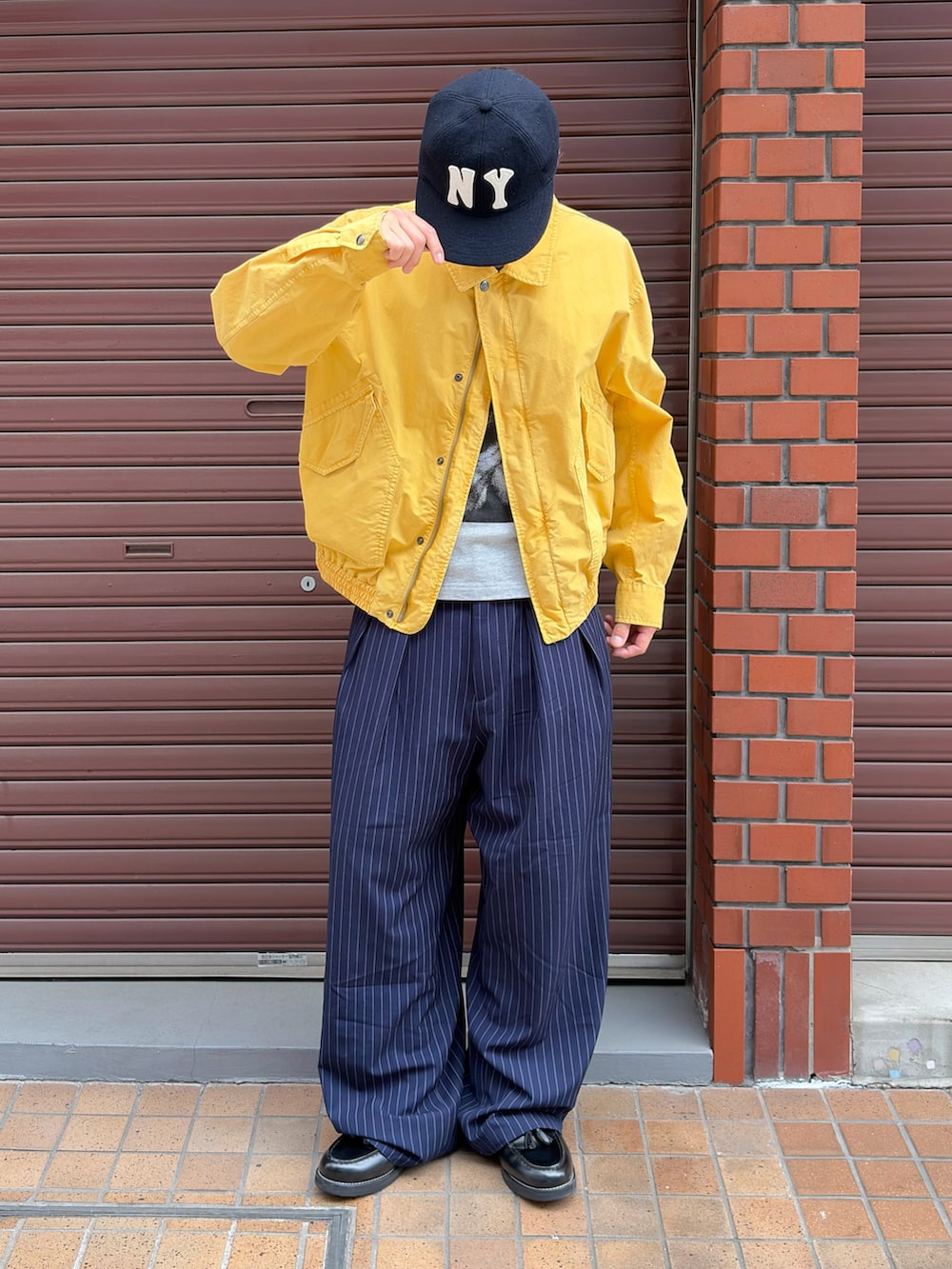 グレー系のTシャツ/カットソー、ブラック系のローファー、イエロー系のミリタリージャケットを着用したメンズの夏コーディネートの2枚目の写真