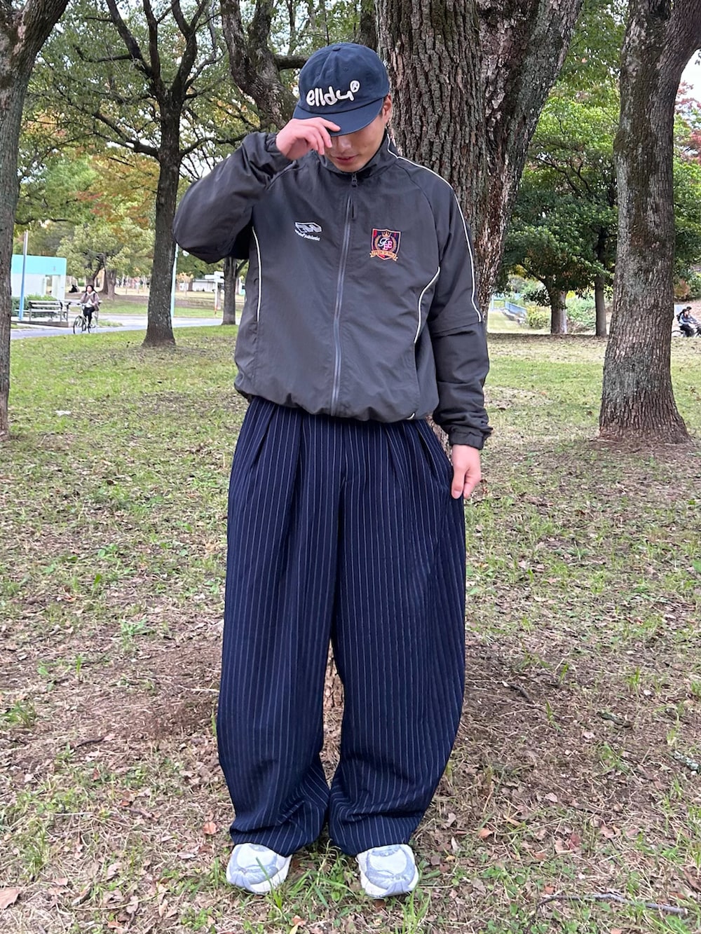 グレー系のナイロンジャケット、ブルー系のスラックス、シルバー系のスニーカーを着用したメンズの冬コーディネートの3枚目の写真