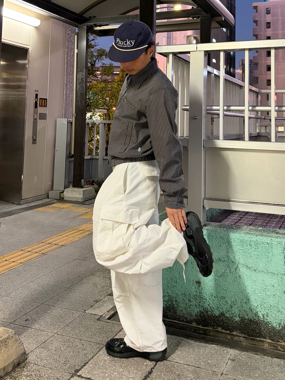 グレー系のブルゾン、ホワイト系のその他パンツ、ブラック系のスニーカーを着用したメンズの冬コーディネートの3枚目の写真