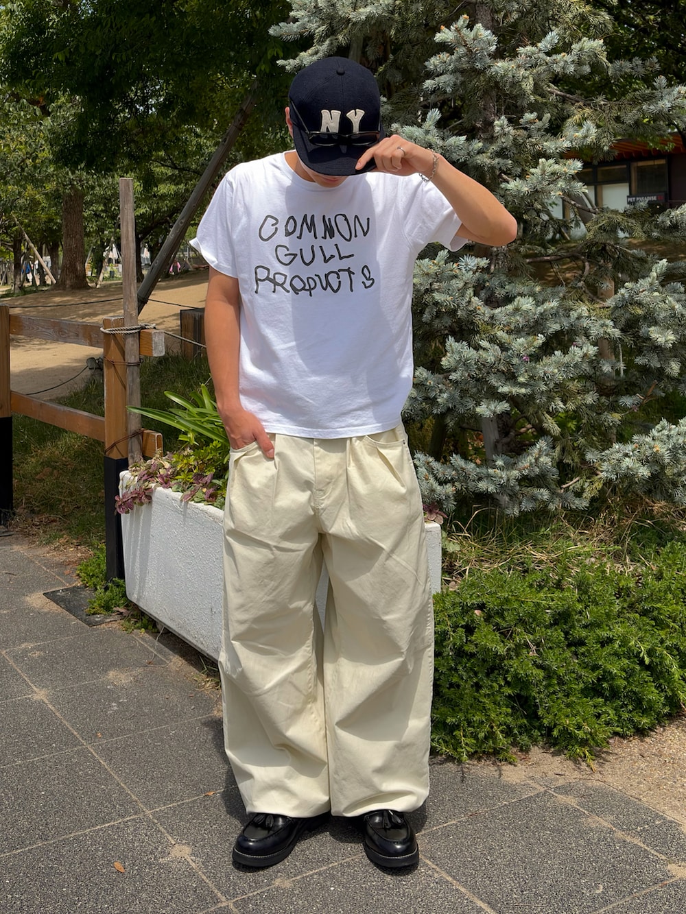 ホワイト系のTシャツ/カットソー、ホワイト系のスラックス、ブラック系のローファーを着用したメンズの夏コーディネートの3枚目の写真