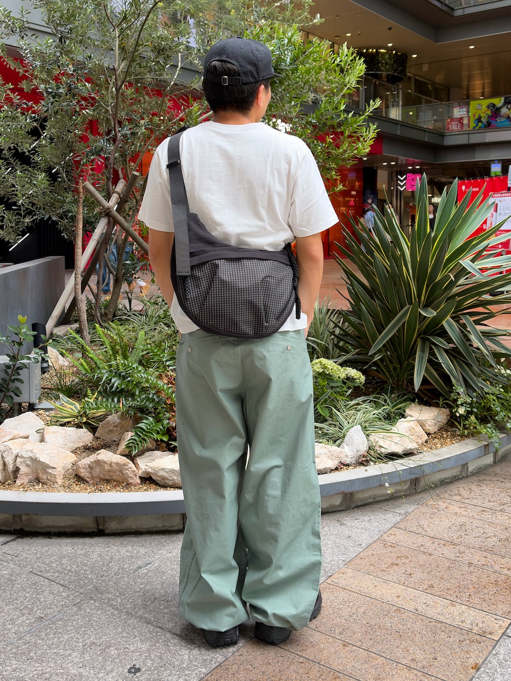 グリーン系のTシャツ/カットソー、グリーン系のスラックス、ブラック系のスニーカーを着用したメンズの夏コーディネートの2枚目の写真