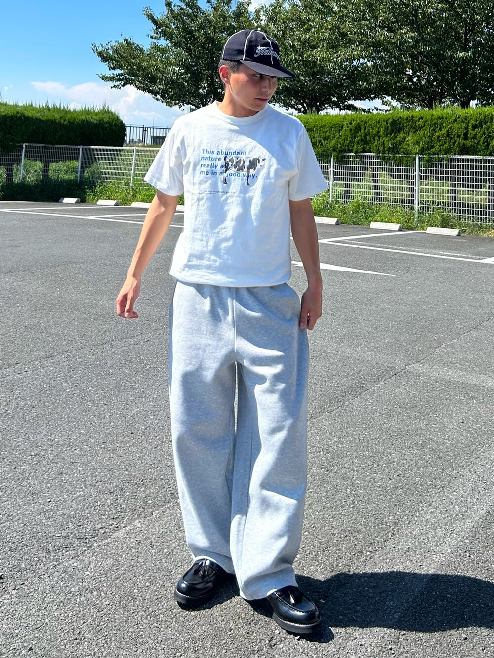 ホワイト系のTシャツ/カットソー、ブラック系のローファー、グレー系のスウェットパンツを着用したメンズの夏コーディネートの2枚目の写真