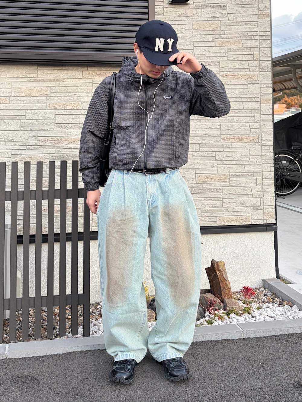 ブルー系のデニムパンツ、ブラック系のナイロンジャケット、ブラック系のスニーカーを着用したメンズの春コーディネートの2枚目の写真