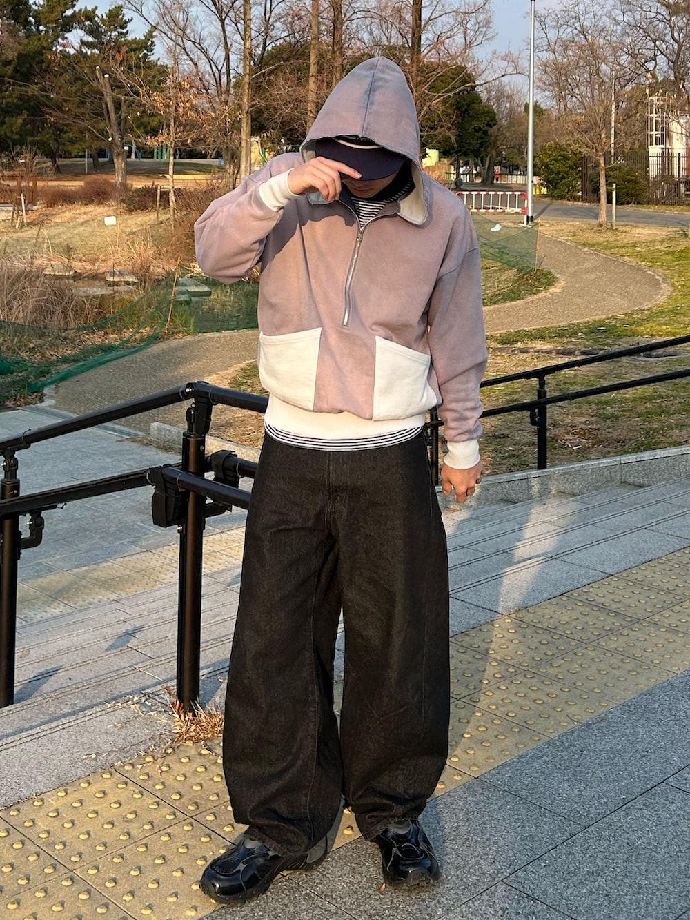 グレー系のパーカー、ブラック系のデニムパンツ、ブラック系のスニーカーを着用したメンズの冬コーディネートの2枚目の写真